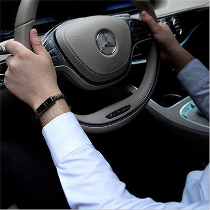 Black leather USB bracelet charger worn on wrist inside a car.