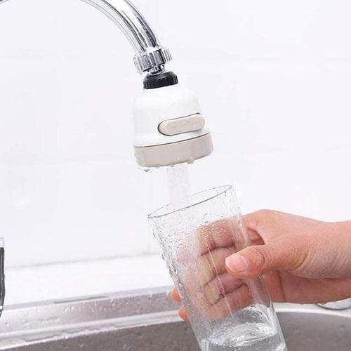 Hand holding white faucet aerator over sink, with water flowing from the outlet