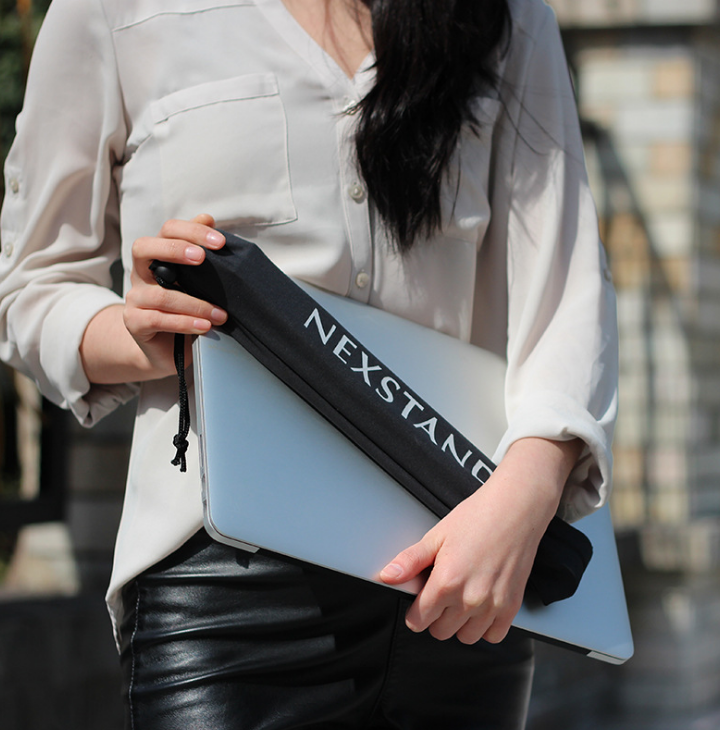 Person holding a black foldable laptop stand with shoulder carry strap