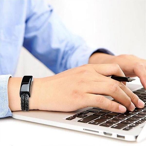 Black leather USB bracelet charger on wrist connected to a laptop.