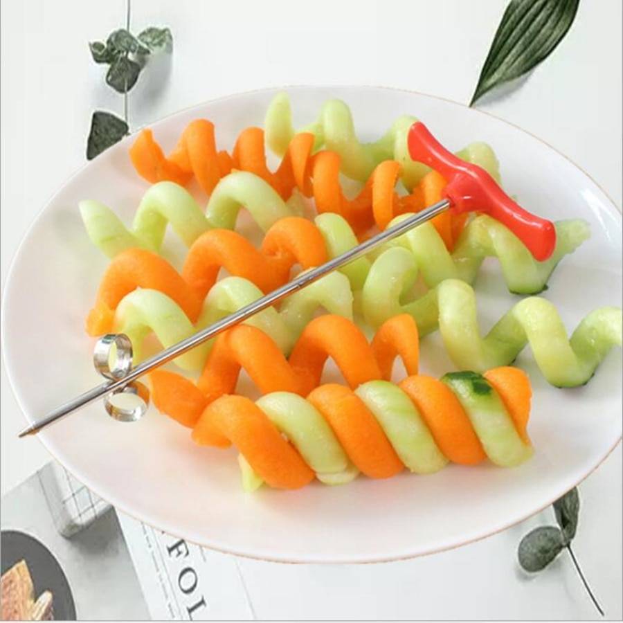 Spiral potato cutter tool resting on a bowl of green and orange spiraled vegetable slices