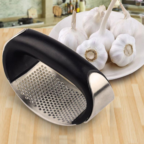 Stainless and black garlic press with perforated basket on counter