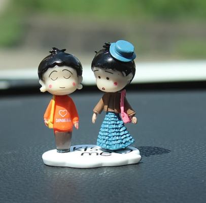 Car dashboard couple figurines holding hands on a round white base