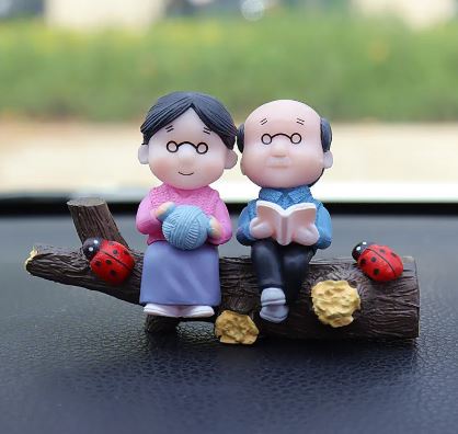 Car dashboard couple figurines standing on dark wood base with yarn heart items