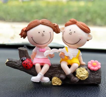 Car decoration couple figurines sitting and holding hands on dark wood base