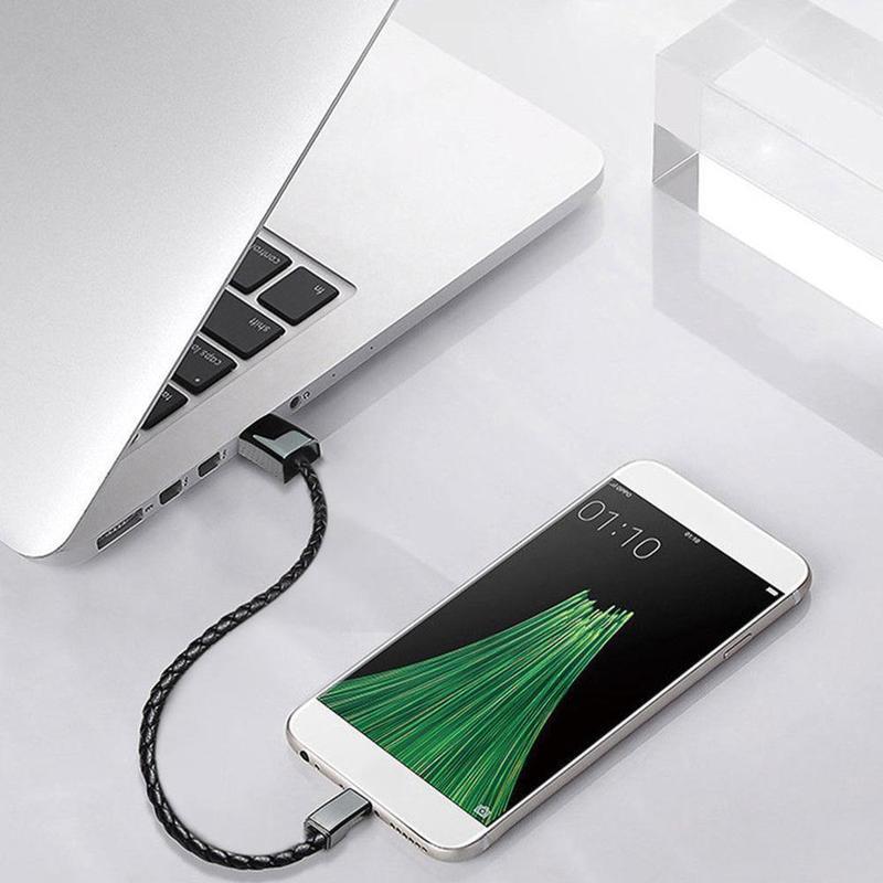 Black braided leather USB bracelet charger plugged into a laptop and phone.