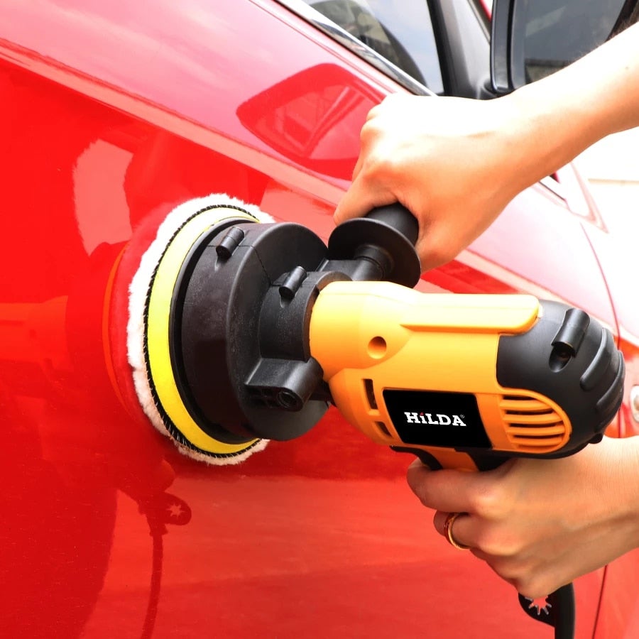 HILDA electric car polisher with yellow handle and circular foam pad on red car panel