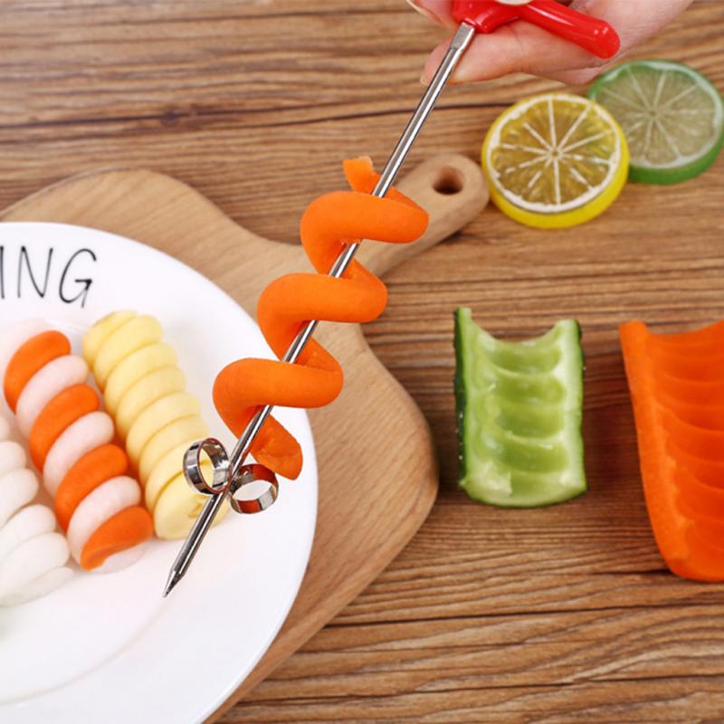 Spiral potato cutter slicing orange and green spirals on a wooden board near citrus