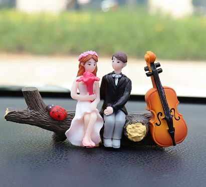 Wedding couple car figurines in formal outfits with orange cello and rose