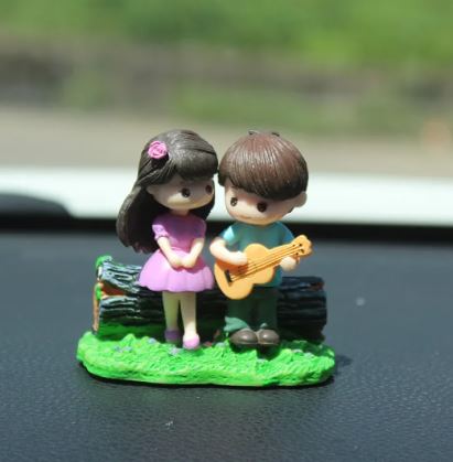 Car dashboard couple figurines playing guitar on green base with musical pose