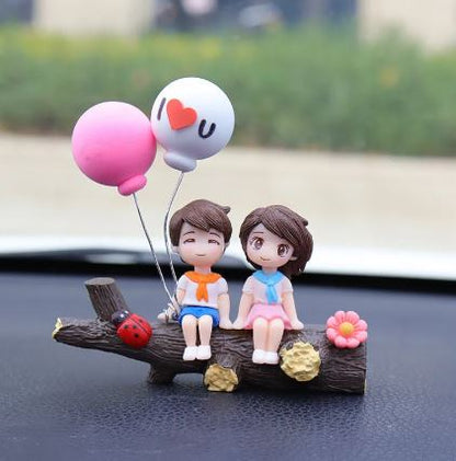 Car dashboard couple figurines holding heart balloon with ladybug and flower decor