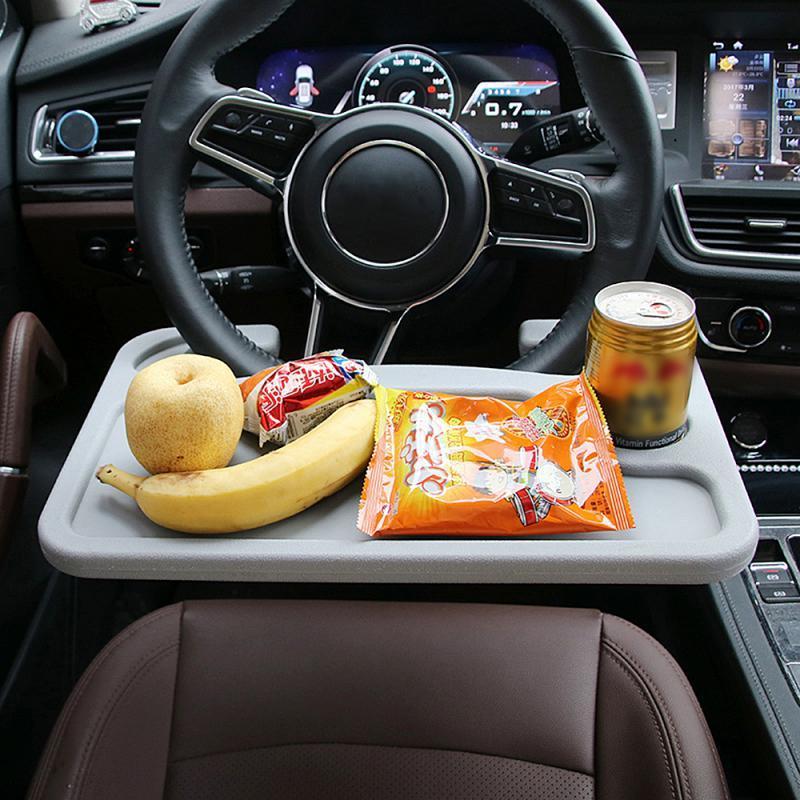 Car steering wheel tray holding a cup and snacks on the front console