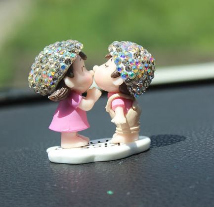 Car dashboard couple figurine with rainbow glitter umbrellas, kissing pose