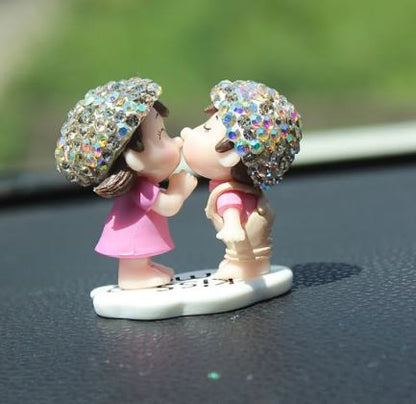 Car dashboard couple figurine with rainbow glitter umbrellas, kissing pose