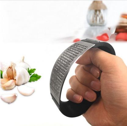Hand using black garlic press to crush garlic cloves
