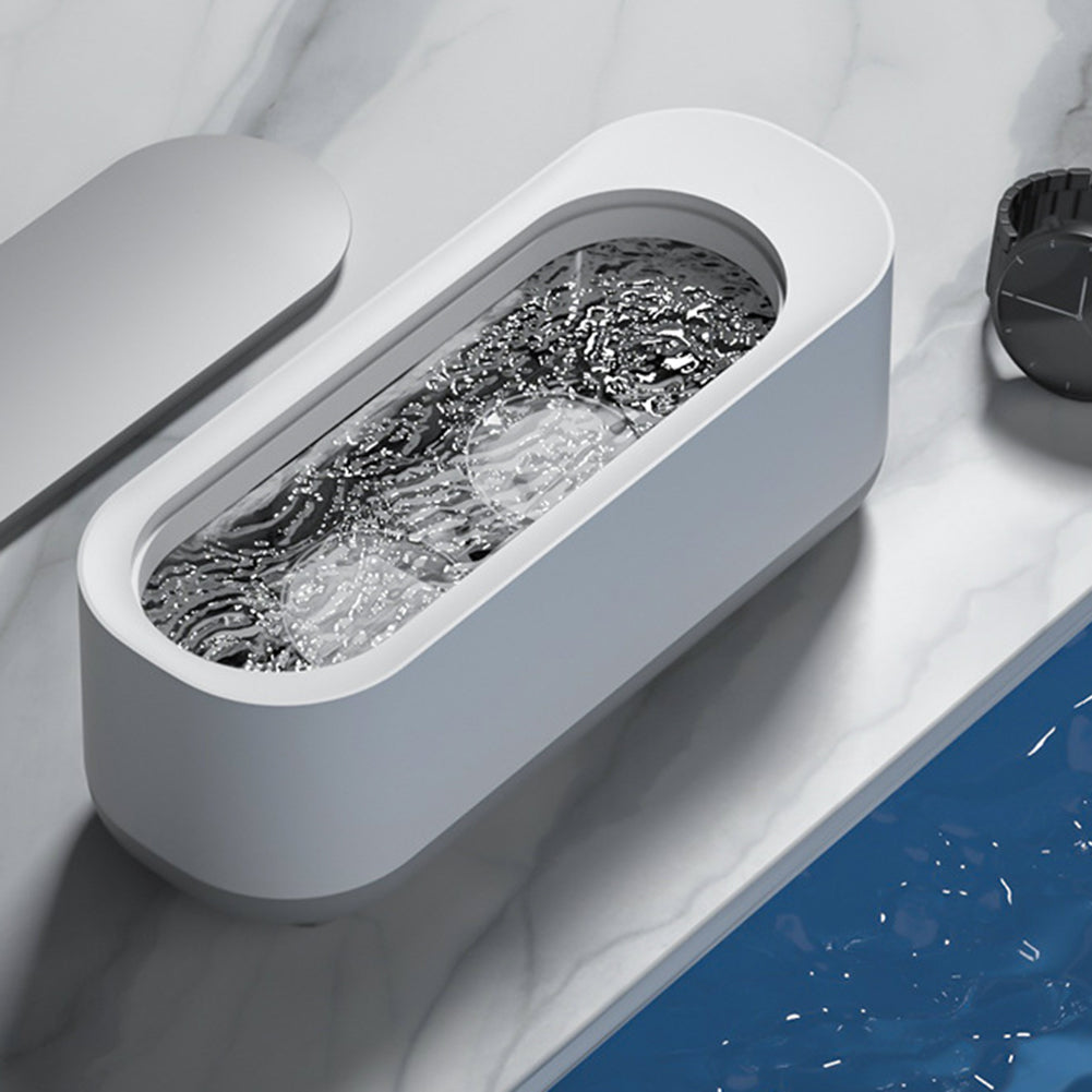 Ultrasonic cleaner tank with gray interior tray and foamy cleaning solution